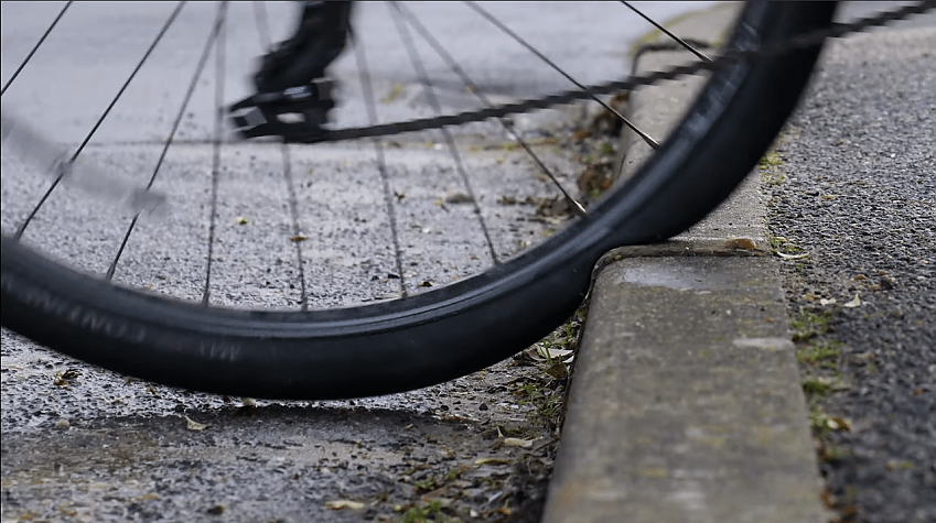 A bicycle wheel pushed up against a curb