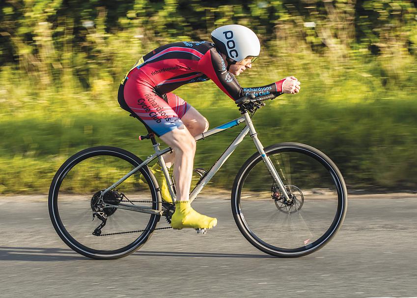 A man is racing on a bike. He's wearing a skin suit and aero helmet