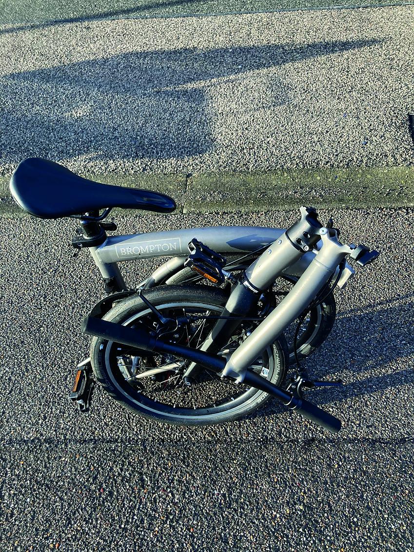 The Brompton bicycle in it's folded state. It is folded up on itself three times to stand saddle-up on the ground in a compact shape