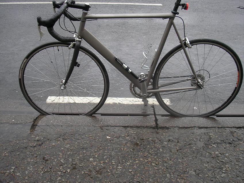 A bicycle stuck in a modern rain gutter running parallel to the road