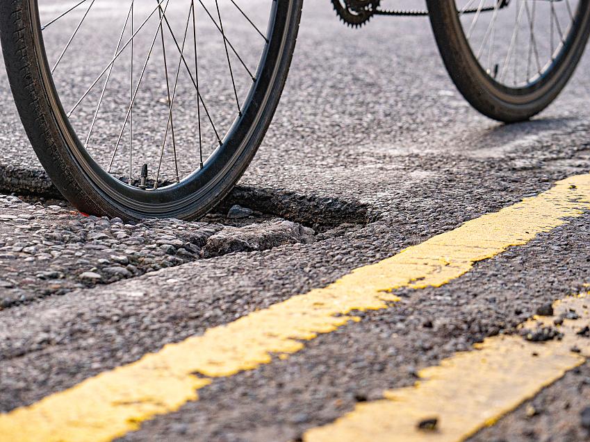 The rear wheel of a bicycle getting stuck in a pothole