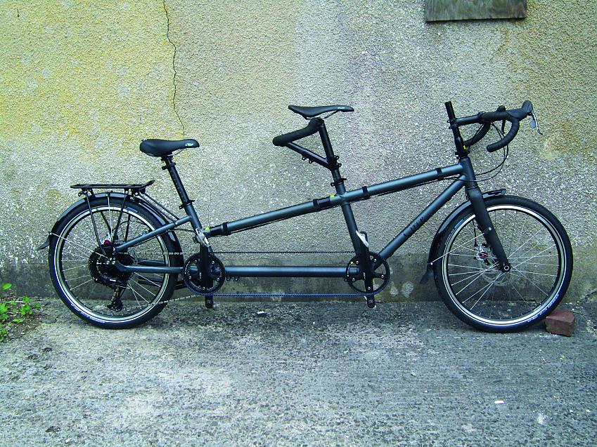 A black tandem bike leaning against a wall