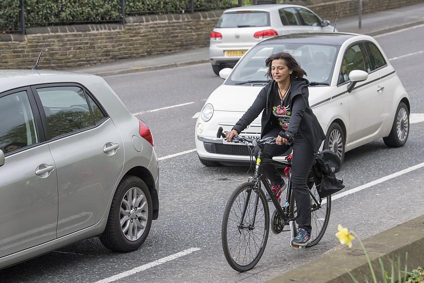 A cyclist cycling in the cycle lane as she passes traffic