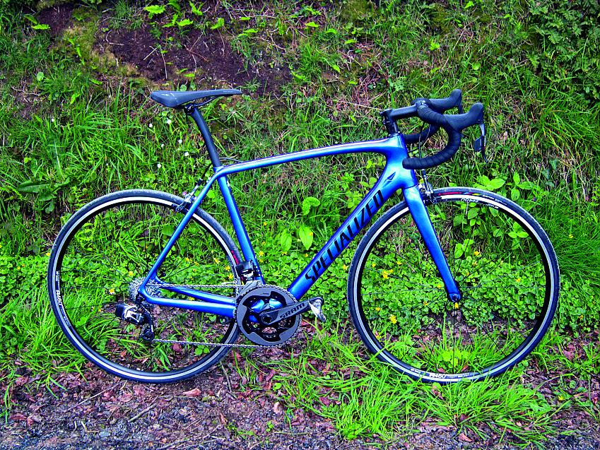 Specialized Tarmac Expert eTAP, a blue road bike leaning against the same verge