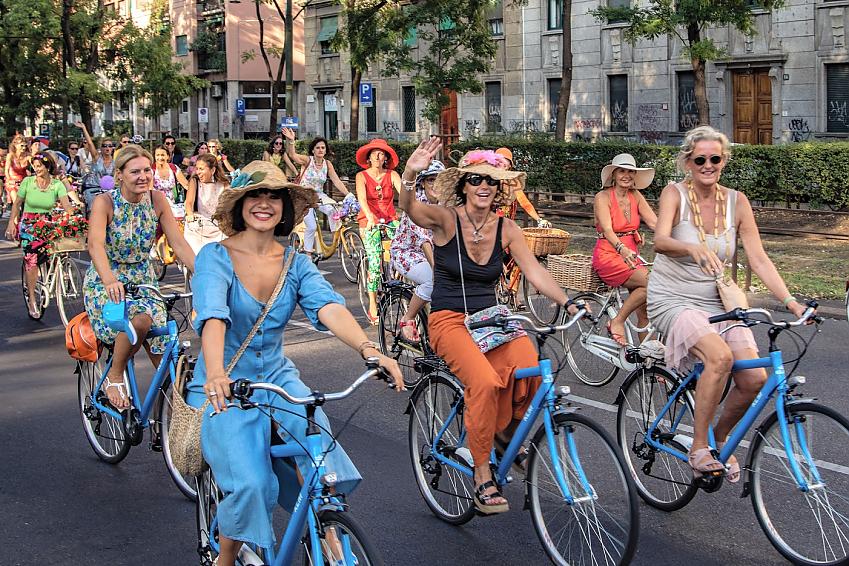 A group of women in fancy clothes cycling and smiling at the camera