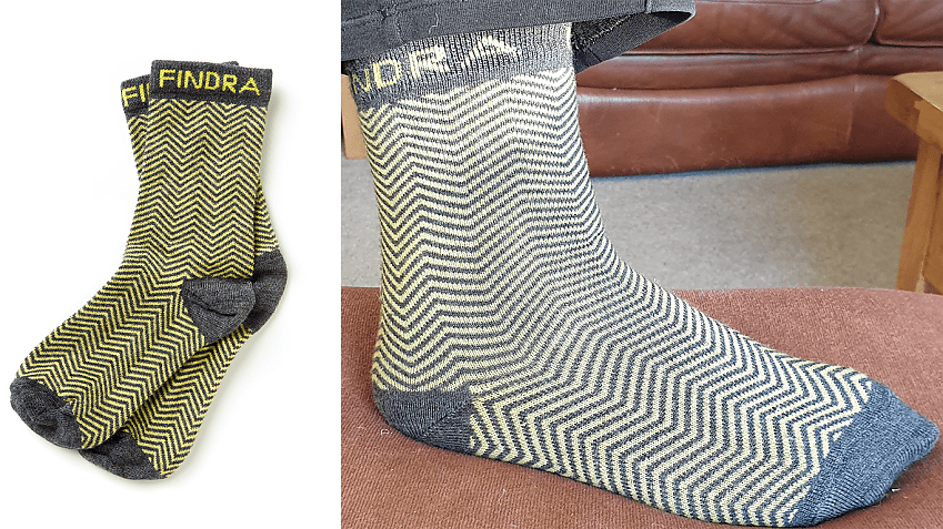 Stock image of FINDRA socks on the left with herringbone yellow pattern on white background, with image on the right showing the sock being worn
