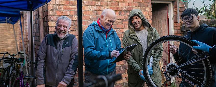 A group of people laughing with a bike on a bike stand