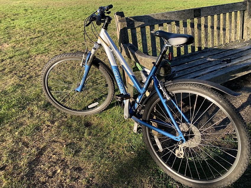 A blue and silver Giant mountain bike leaning against a park bench