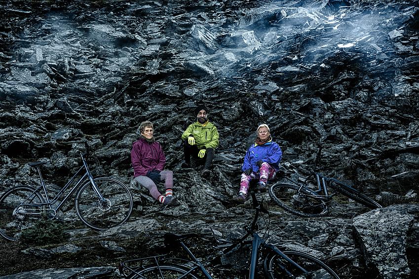 Three people are sitting on a mountain with the three Islabikes Icons bikes around them