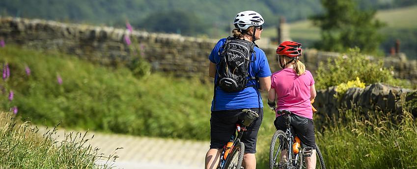 Mother and daughter cyclists pause for breath on a lane with dry stone walls