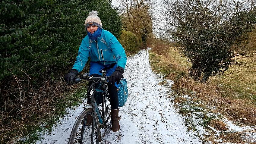 A cyclist in winter riding next to frozen canal