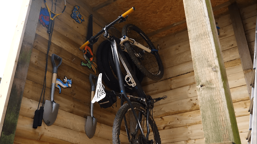 A bike attached to the ceiling of a shed