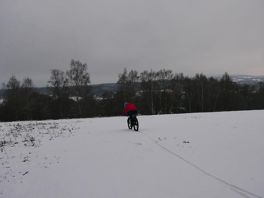 Cyclist heading down a snowy hill