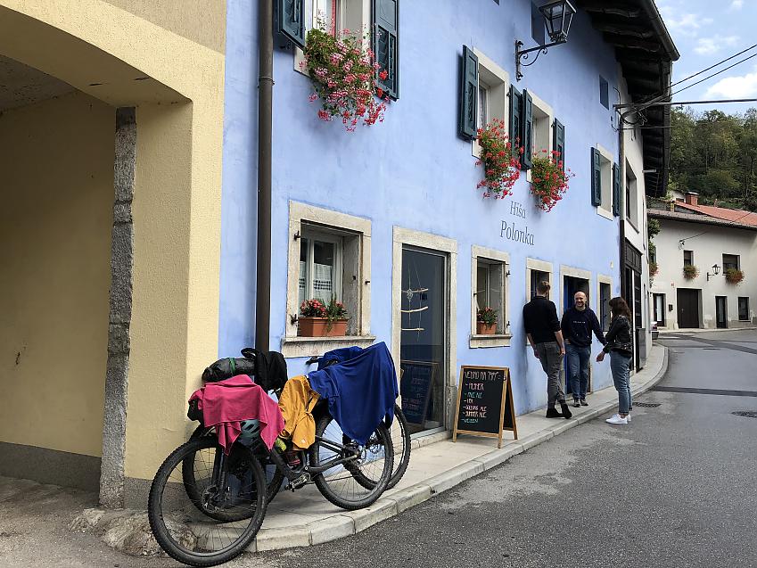 A bicycle is draped with drying clothes and leaning against the wall of a cafe