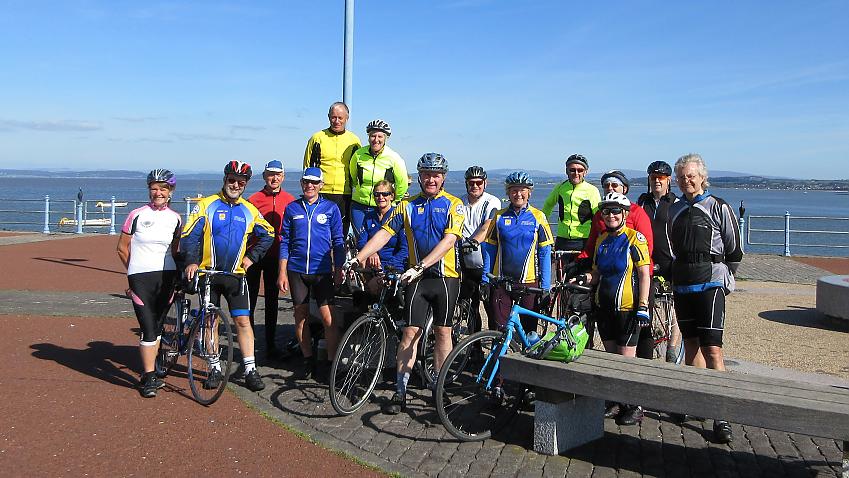 A group of cyclists and their bikes are gathered on the seafront in Morecambe