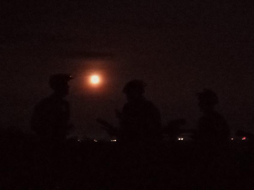 An MTB group looks at the full moon from Holmbury Hill, the lights of Gatwick airport in the distance