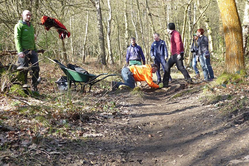 A group of people dressed in work clothes are doing improvement work on an off-road trail