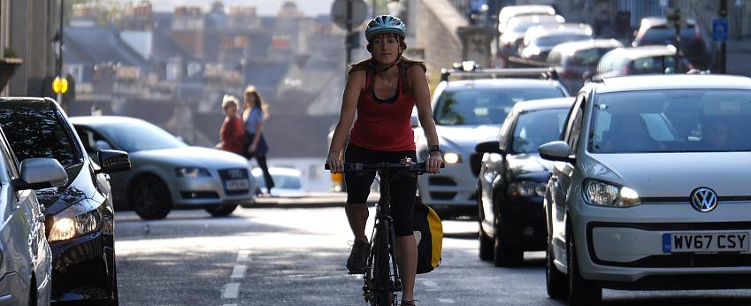 Woman cycling on cycle lane through heavy traffic