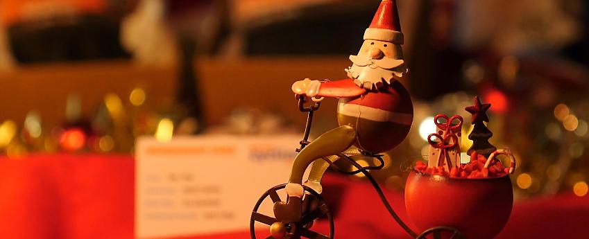 A wooden Santa toy in front of a low-lit festive scene