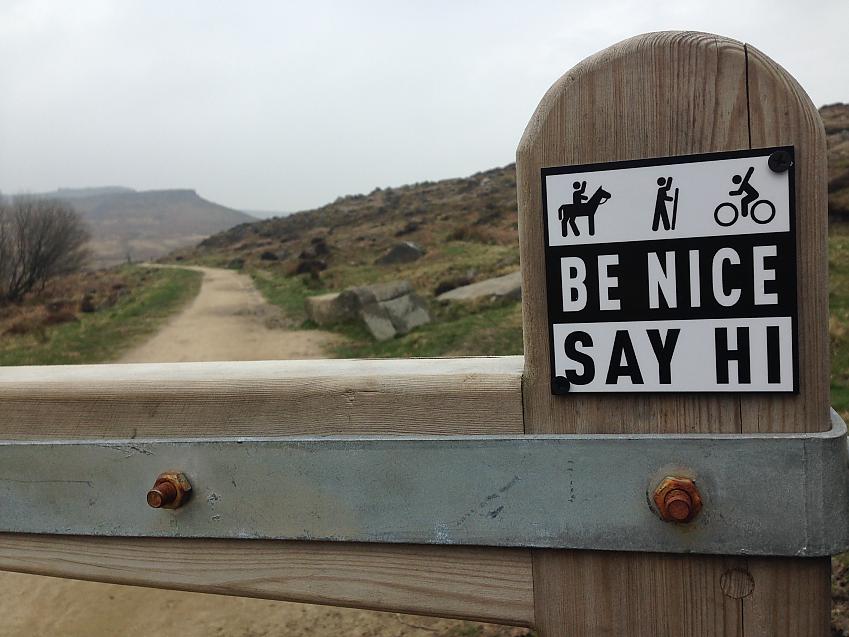 Be Nice Say Hi sign on a moorland track