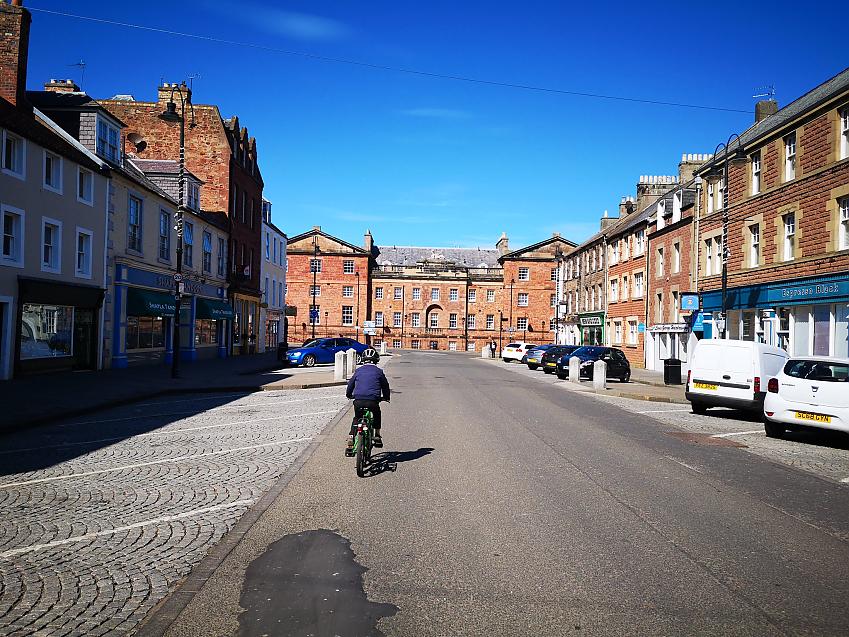 A small child cycling on an empty high street