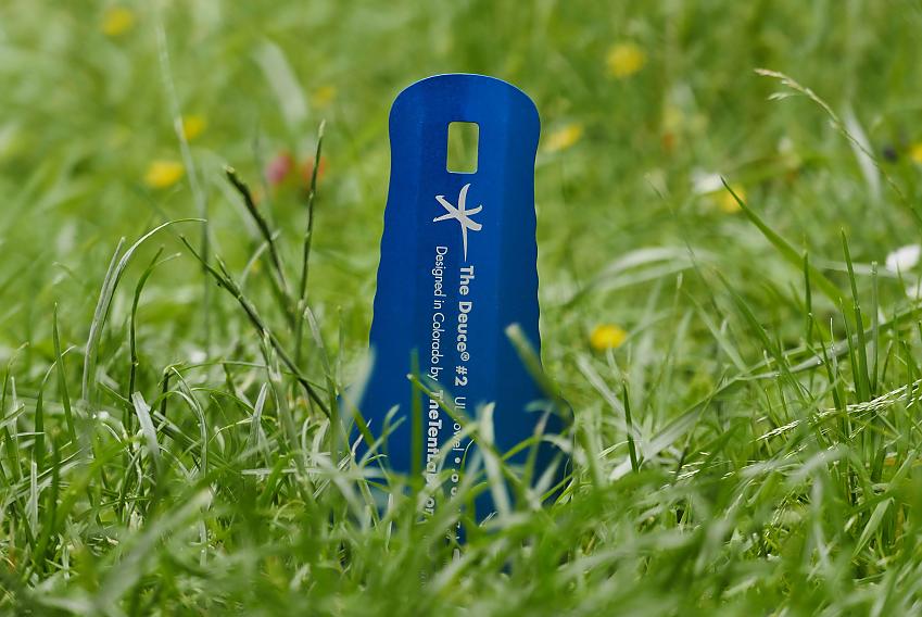 A blue camping trowel stuck in the ground