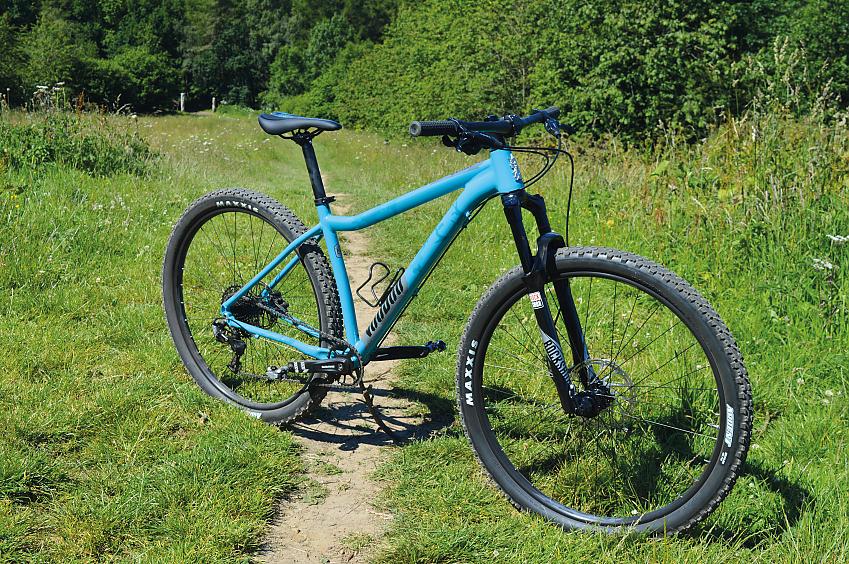 A sky blue mountain bike with front suspension propped up in a field