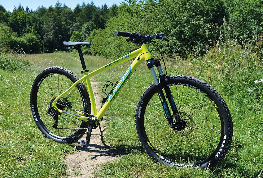 A yellow mountain bike with front suspension, propped up in the same field