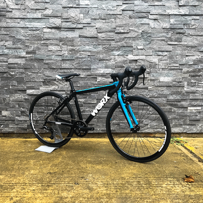 Worx JA-24, a blue and black children's road bike, leaning against a wall