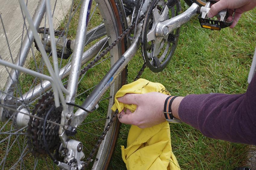 Use a cloth held around the chain and spin the pedals to clean off dirt