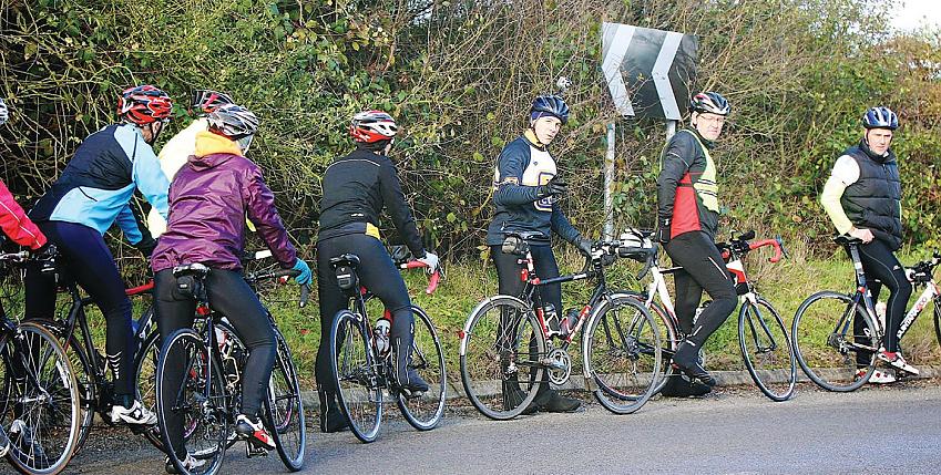 A group of cyclists pause at the bottom of a hill
