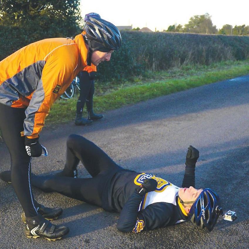 A cyclist lies on the ground, pretending to have fallen off