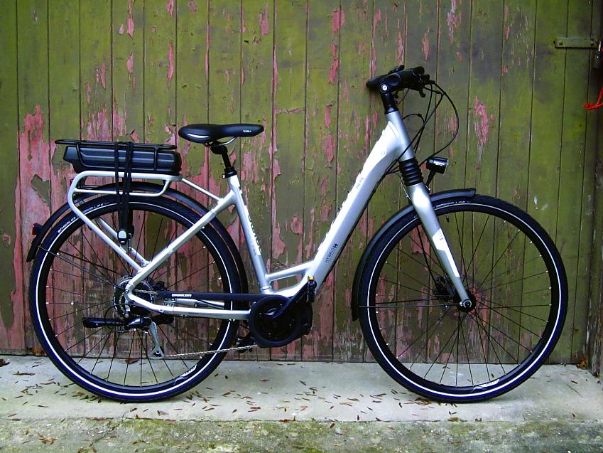 A silver e-cycle with the battery on the rear rack