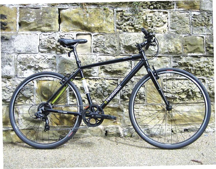 Revolution Courier Race, a black hybrid bike with a flat handle bar leaning against a wall