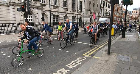 A big group of people are cycling along a London street. There is a mix of bikes and people
